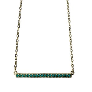 May include: A gold chain necklace with a turquoise bar pendant. The bar is set with small turquoise stones.