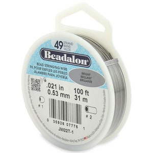 May include: A spool of 49 strand silver beadalon bead stringing wire. The spool is labeled with the text "Beadalon", "Bead Stringing Wire", "Fil pour enfiler les perles", "Alambre para Joyería", "Bright", "Brilliant", "Brillante", ".021 in", "0.53 mm", "100 ft", "31 m", "JW22T-1", and a barcode.