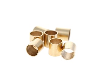 May include: A group of six gold-colored metal rings, each with a smooth, round opening. The rings are arranged in a loose pile, with some overlapping.
