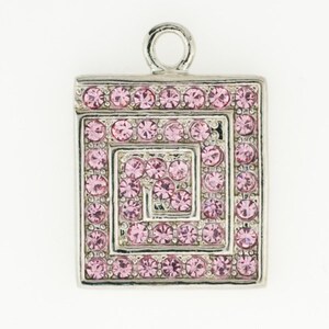 May include: Silver-toned square pendant with a spiral design, encrusted with small, round, pink crystals. The pendant has a loop at the top for attaching to a chain or bracelet. The crystals are evenly spaced, creating a sparkling effect.