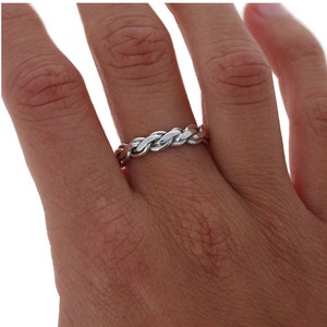 May include: A silver and copper braided ring worn on a finger.