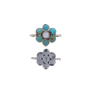 May include: Silver flower-shaped clasp with turquoise stones and a clear rhinestone in the centre. The clasp is open on both sides, showing the back with a decorative design.