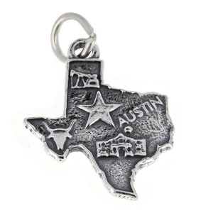 May include: Silver charm shaped like the state of Texas with a star, a longhorn steer, and the word "Austin" on it.