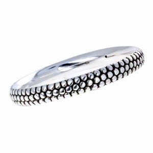 May include: A silver bangle bracelet with a textured, beaded design.