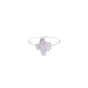 May include: A silver ring with a Texas-shaped design. The Texas outline is filled with small, light pink gemstones. The ring has a thin, silver band.