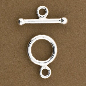 May include: Silver toggle clasp with a round ring and a bar with rounded ends. The clasp is a popular choice for necklaces, bracelets, and other jewelry.