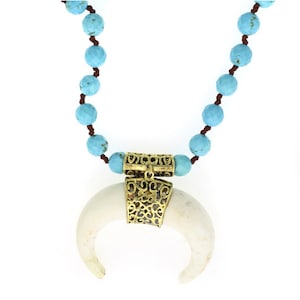 May include: A turquoise bead necklace with a white bone pendant and a gold filigree charm.