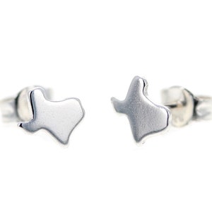 May include: A pair of silver stud earrings shaped like the state of Texas.