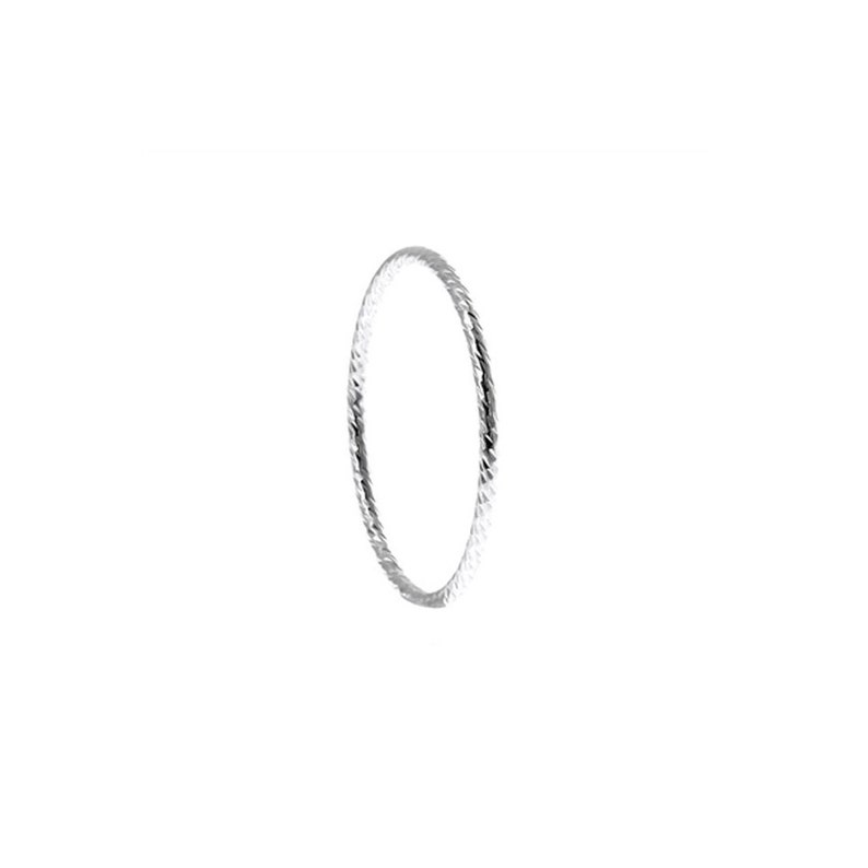 May include: A thin, circular silver ring featuring a textured, faceted surface that reflects light. The band has a consistent, slender profile and a metallic, reflective finish, creating a simple, continuous loop design without any additional stones or settings.