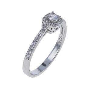 May include: A silver ring with a square-shaped center stone surrounded by smaller stones. The band is also set with smaller stones.