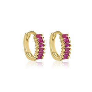 May include: A pair of gold hoop earrings with a row of pink baguette-shaped stones around the hoop.