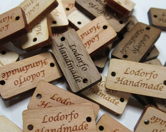 May include: A pile of wooden tags with the text "Lodorfo Handmade" engraved on them. The tags are various shades of brown and have two holes for string or ribbon.