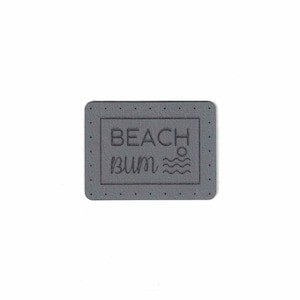 Può includere: Toppa in pelle grigia con il testo "BEACH bum" e una grafica di sole e onde.