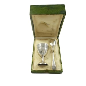 May include: A white ceramic mug with a black handle and the text "But First, Coffee" in a handwritten style. The mug is on a white surface. The mug is approximately 4 inches tall.