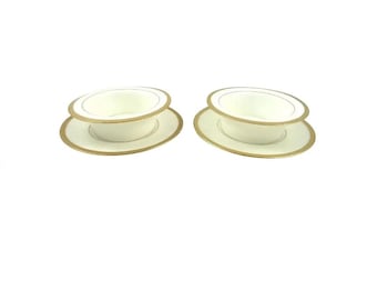 May include: Two white porcelain bowls with gold trim, each sitting on a matching saucer. The bowls and saucers have a delicate gold rim.
