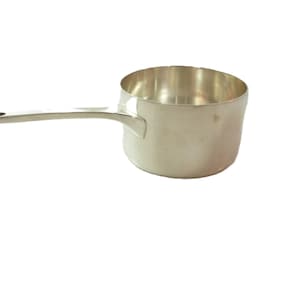 May include: A silver saucepan with a handle. The saucepan is small and has a rounded bottom.