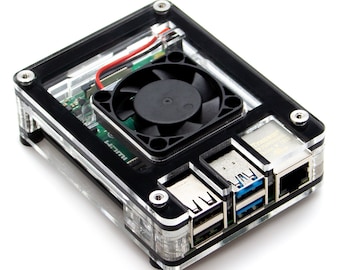 Op de afbeelding: Zwarte Raspberry Pi-behuizing met een transparante acrylafdekking, een kleine ventilator en meerdere poorten, waaronder USB en Ethernet.