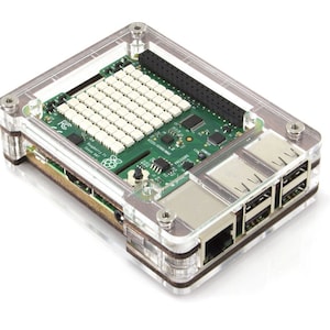 Op de afbeelding: Een transparante plastic behuizing voor een Raspberry Pi-computer. De behuizing heeft een bruine houten accent en bevat uitsparingen voor de poorten op de Raspberry Pi.