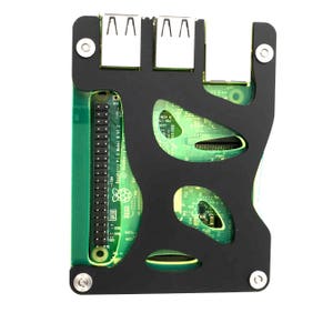 May include: A black plastic case with cutouts for a Raspberry Pi 3 Model B V1.2 circuit board. The board is green and has a Raspberry Pi logo. The case has four screw holes and two USB ports.