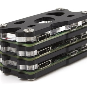 Könnte beinhalten: Ein stapelbares elektronisches Gerät in Schwarz und Grün mit mehreren Anschlüssen. Das Gerät hat ein transparentes Kunststoffgehäuse und ist aus Metall.