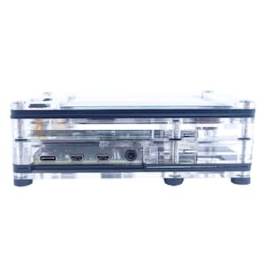 May include: A clear plastic case with black accents and a small circuit board inside. The case has three ports on the side, including a micro USB port, a mini HDMI port, and a headphone jack.