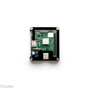May include: A black case with a green circuit board inside. The board has a small silver heat sink and several connectors, including a micro-USB port, an HDMI port, and a micro-SD card slot.