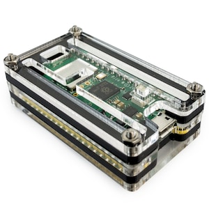 Może przedstawiać: Przezroczysta obudowa akrylowa z czarnymi akcentami dla Raspberry Pi Pico W. Obudowa ma szczelinę na port USB-C i mały otwór na przycisk resetowania. Raspberry Pi Pico W jest widoczny wewnątrz obudowy.