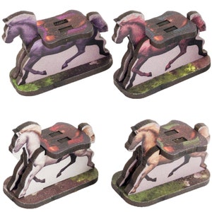 May include: Four wooden horse figurines with different colored coats. Each horse is in a running pose with a saddle and a rider's stirrups. The horses are on a brown base with a green and brown grass design.