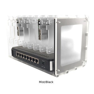 May include: A clear acrylic case with a black network switch and five slots for Raspberry Pi boards. The case has a frosted finish and the text "Mist/Black" is printed on the bottom.