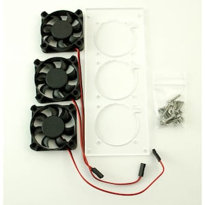 Op de afbeelding: Een bovenaanzicht van een computerkoelsysteem. Drie zwarte ventilatoren zijn gemonteerd op een helder acryl paneel met drie cirkelvormige uitsparingen. Rode draden verbinden de ventilatoren. Een klein zakje met schroeven is ook inbegrepen.