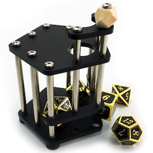 May include: A black metal dice tower with a wooden knob on top. The tower has a cage-like design with metal bars. Several gold and black dice are scattered around the tower.