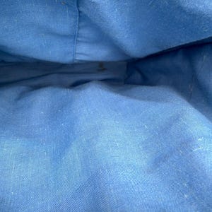 K&ouml;nnte beinhalten: Innenansicht einer blauen Stofftasche. Das Innere der Tasche ist einfarbig hellblau, mit sichtbaren N&auml;hten und einer leicht strukturierten Oberfl&auml;che. Der Stoff scheint ein robustes Material zu sein, m&ouml;glicherweise Segeltuch oder ein &auml;hnliches Textil.