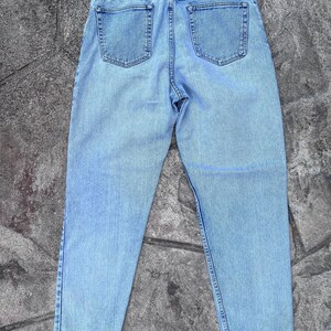 May include: Light blue denim jeans with a classic five-pocket design. The jeans have a high waist and a relaxed fit, with a faded wash for a vintage look. The back view shows the pockets and the stitching details.