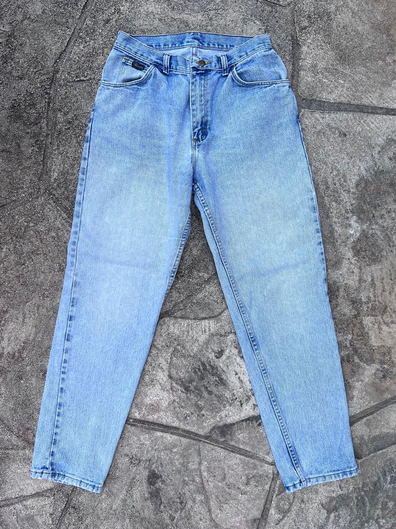 May include: Light blue denim jeans with a classic five-pocket design. The jeans have a straight leg cut and a button and zipper closure. The Lee logo is visible on the front pocket. The jeans are made of a durable denim material.