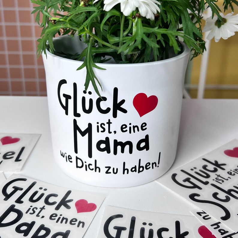 Schwarzer Sticker, Glück ist, eine Mama wie dich zu haben auf einem weißen Blumentopf mit einem roten Herz als Geschenk für Mama.
