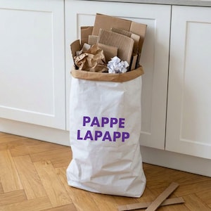 Papiersack Pappelapapp mit lila Schriftzug, gefüllt mit Pappe und Kartons zur Altpapier-Aufbewahrung neben der Küchenzeile