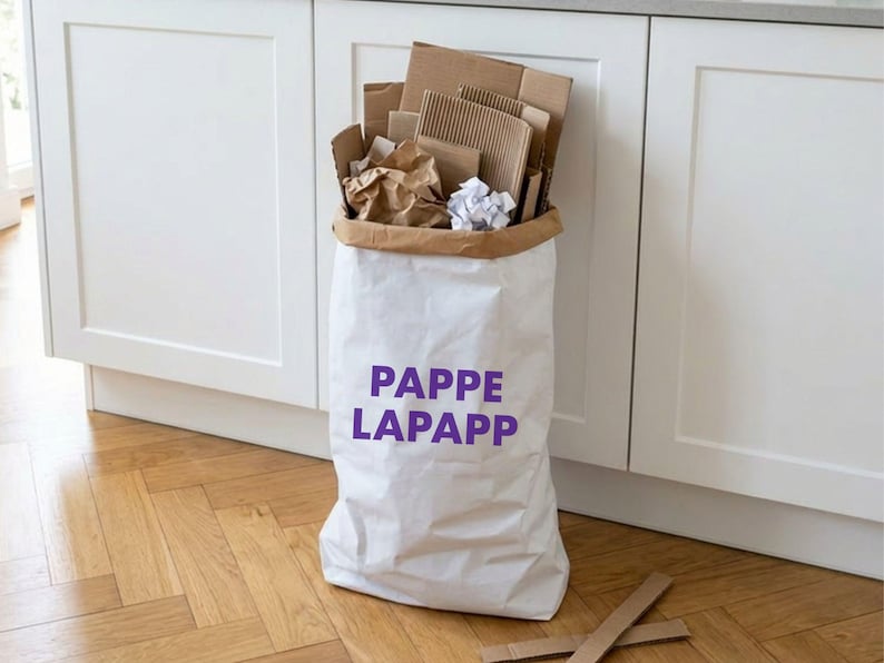 Papiersack Pappelapapp mit lila Schriftzug, gefüllt mit Pappe und Kartons zur Altpapier-Aufbewahrung neben der Küchenzeile