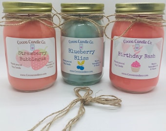May include: Three glass jars with gold lids and twine tied around the tops. Each jar contains a soy candle with a different scent and label. The scents are Strawberry Bubblegum, Blueberry Bliss, and Birthday Bash. The candles are made in Waterbury, CT and are 16 ounces.