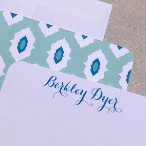 May include: White stationery with a blue and green patterned border and the name "Berkeley Dyer" written in blue cursive script.