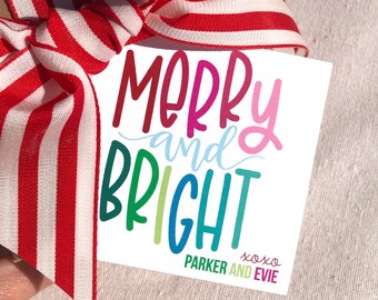 May include: A white gift tag with the words "MERRY and BRIGHT" in colorful lettering, tied with a red and white striped ribbon. The tag also includes the text "PARKER AND EVIE xoxo".