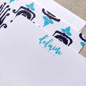 May include: White stationery with a blue and black ikat pattern border. The name "Delainie Teepe" is printed in blue cursive script.