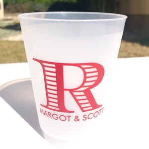 May include: A white frosted plastic cup with a red striped letter "R" and the text "MARGOT & SCOTT" printed on the front.