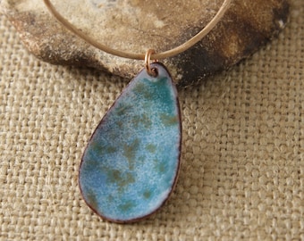 May include: A teardrop-shaped pendant necklace with a blue and green enamel finish. The pendant is attached to a brown leather cord.