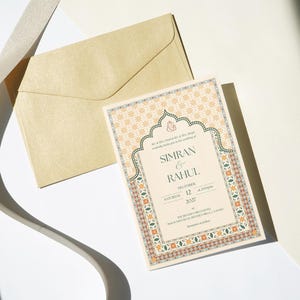 May include: A wedding invitation with a beige background and ornate border, featuring the names "Simran & Rahul" and event details. A matching envelope and decorative ribbon are also present.
