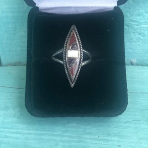 May include: A silver ring with a diamond-shaped stone set in the center. The stone is made of various colors of red, white, and black.
