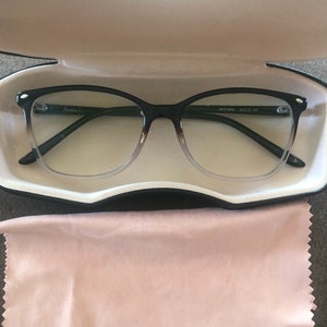May include: Black and green eyeglasses with a clear lens and a brown tortoiseshell frame. The glasses are in a black case with a pink microfiber cleaning cloth.