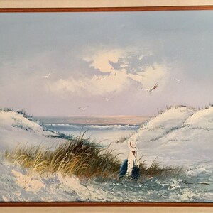 May include: A painting of a seascape with a lone figure sitting on a sandy beach, looking out at the ocean. The sky is a soft blue with white clouds, and there are a few seagulls flying overhead.