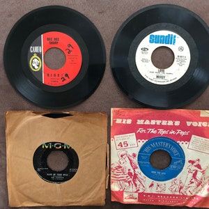 May include: Four vintage vinyl records, two black and two brown, with labels featuring the artists Dee Dee Sharp, The Gimiks, and The Tops in Pops. The records are in their original paper sleeves.