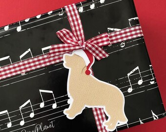 May include: A wrapped gift with black paper printed with musical notes, tied with a red and white checkered ribbon. A light brown dog-shaped tag wearing a Santa hat is attached to the ribbon. The gift is on a red background.