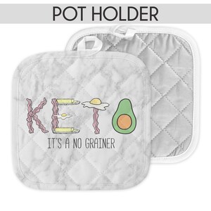 May include: White pot holder with a marble pattern and the text "Keto It's a No Grainer" in black. The text is surrounded by illustrations of bacon, eggs, and avocado.